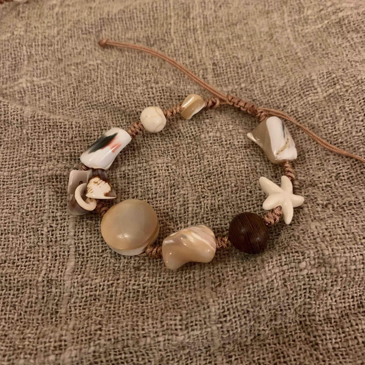 Handmade beach bracelet with seashells, starfish, and natural beads on macrame cord