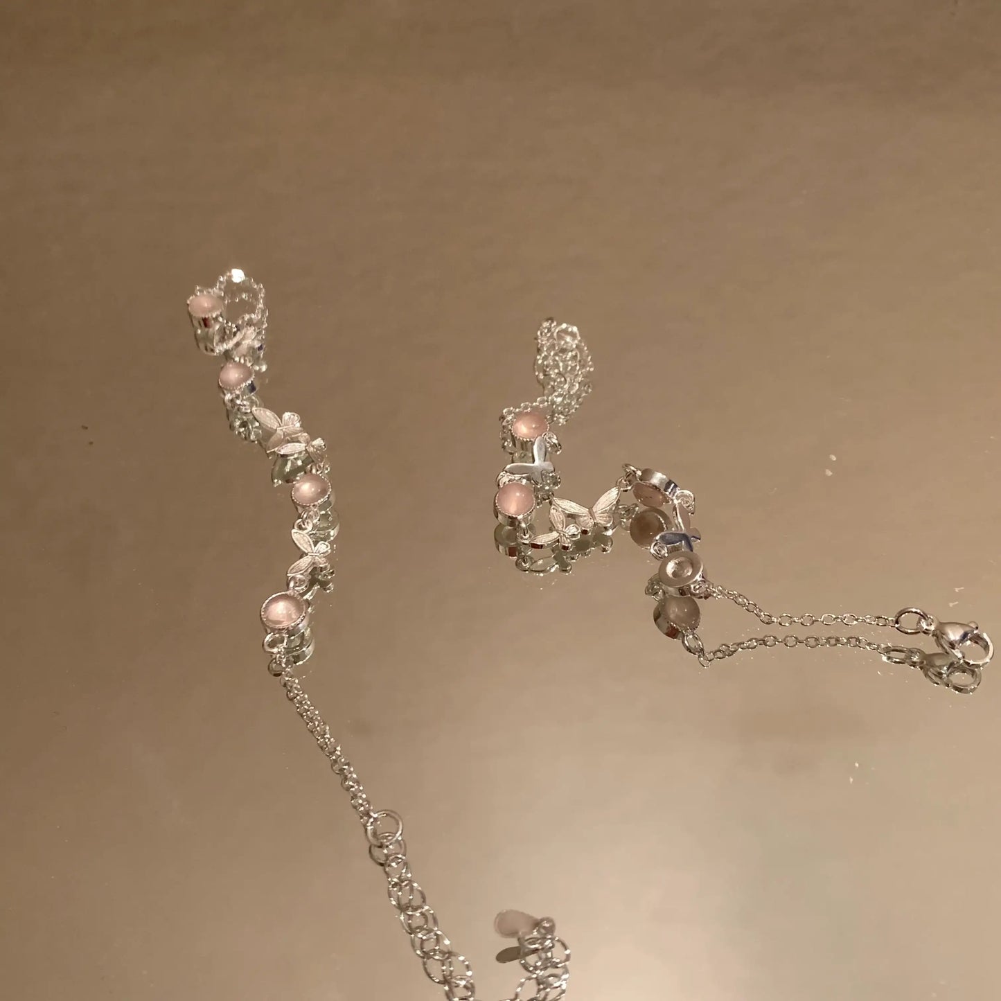 Delicate silver necklace with pink gemstones and butterfly charms, minimalist jewelry design