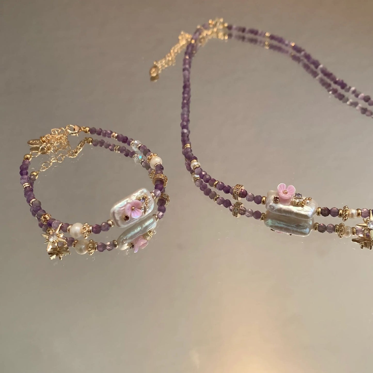 Purple beaded necklace and bracelet set with pearl and pink flower charms, minimalist jewelry design