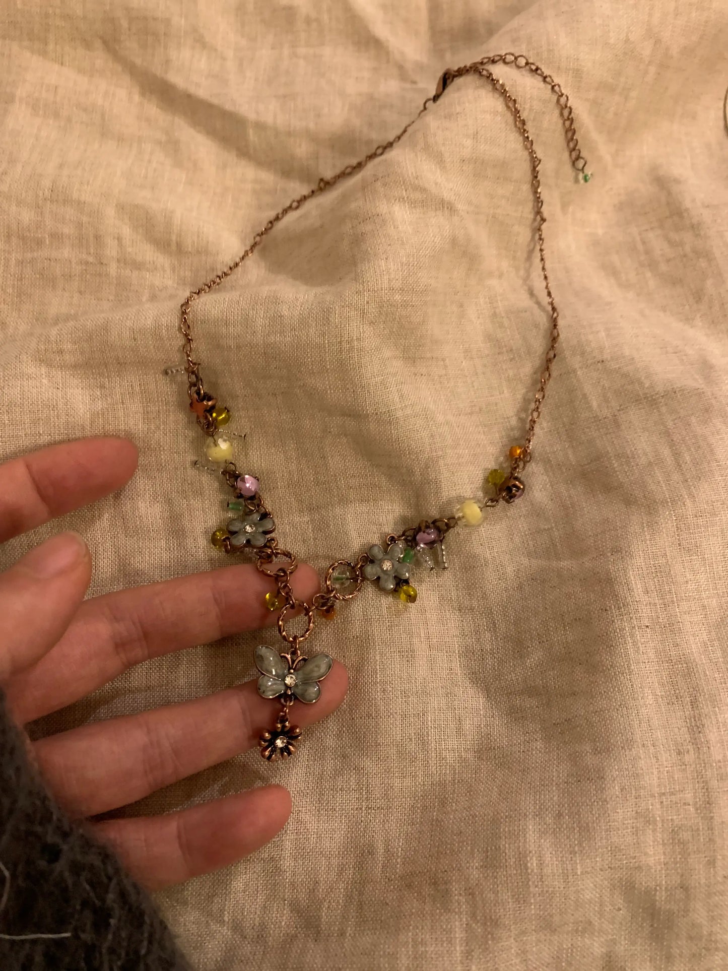 Delicate flower charm necklace with colorful beads and butterfly pendant, handcrafted jewelry piece
