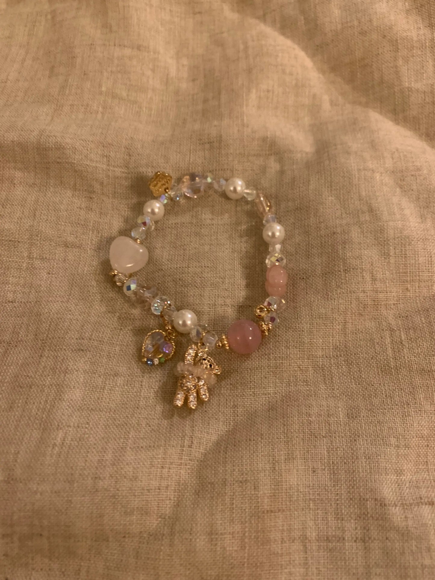 Pink pearl and crystal beaded bracelet with gold charms on linen, gift-ready handmade jewelry