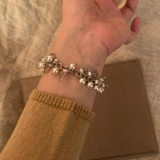 Elegant pearl and star charm bracelet on wrist, minimalist jewelry design