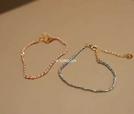 Delicate gold chain bracelets with pink and blue enamel beads, minimalist jewelry design