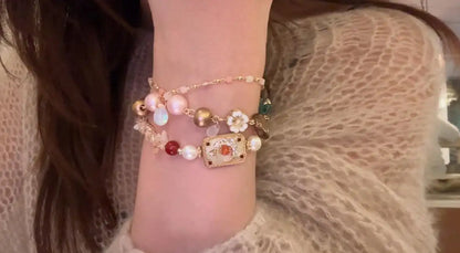 Layered boho bracelet set with pearls, floral charm, and gold beads on wrist