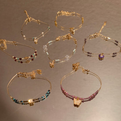 Set of gold and beaded bracelets on a reflective surface
