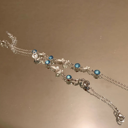 Minimalist silver necklace with blue gemstones and floral charms, handcrafted for everyday elegance