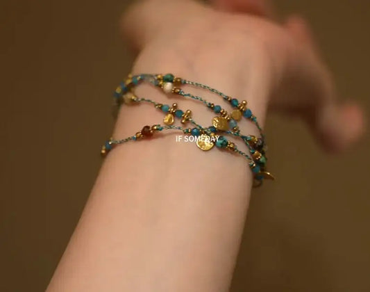 Layered turquoise and gold beaded bracelet set on wrist, minimalist boho style