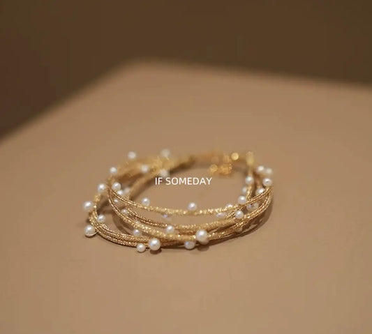 Delicate gold multi-layer bracelet with pearl accents, minimalist jewelry design