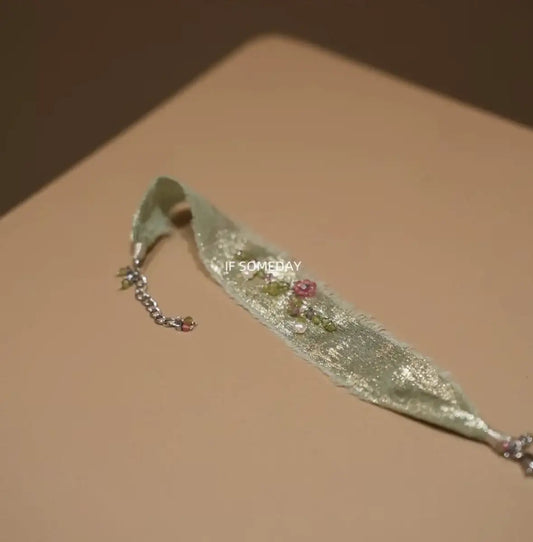Delicate mint green ribbon bracelet with floral beads and chain accent, minimalist jewelry design